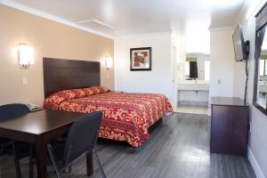 a hotel room with a bed and a table and a desk at Starlite Motel in San Antonio