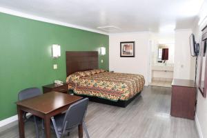 a bedroom with a bed and a table and a desk at Starlite Motel in San Antonio