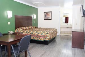 a hotel room with a bed and a table and a desk at Starlite Motel in San Antonio