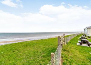 a fence next to a beach with picnic tables at Castaways Holiday Park in Bacton