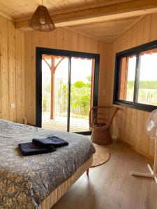 a bedroom with a bed and a large window at Cabane Alizée, Vensac Océan, Montalivet in Vensac