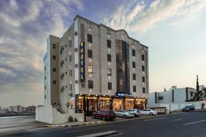 a large building with cars parked in front of it at The Palace Hotel Suites - Al Badea in Abha