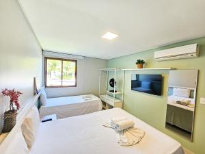 a small room with two beds and a tv at Carneiros Beach Resort in Praia dos Carneiros +291 photos