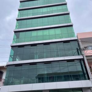 ein hohes grünes Gebäude mit Glasfenstern in der Unterkunft En el Centro de Matagalpa in Matagalpa