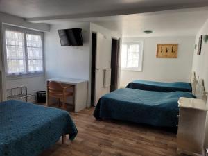 a room with two beds and a table and a desk at Le Saint Benoist in Aizenay
