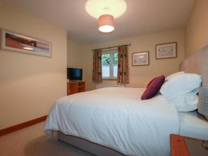 a bedroom with a white bed and a window at The Old Milking Parlour in Par