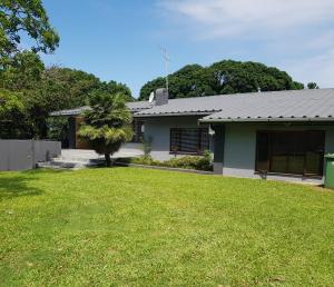 a house with a green lawn in front of it at Sea La Vie- beach cottage in Port Edward