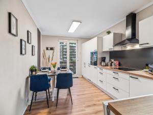 a kitchen with white cabinets and a table with blue chairs at Modernes 2 Zimmer Apartment mit Balkon, zentrale Lage in Bremen