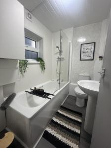 a white bathroom with a tub and a sink at Stylish Two Bedroom Apartment in Cardiff