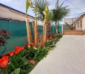 un giardino con fiori rossi e palme di Maison chez nous a Saint-Priest Altre 6 foto
