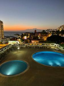 two large swimming pools on a patio with the ocean at Copacobana Ocean View Playa Las Americas in Costa de Adeje