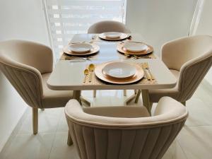 a dining room table with chairs and plates on it at Apartamento Marbella Piso 28 - Playa in Cartagena de Indias