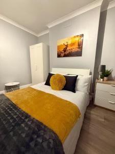 a bedroom with a large bed with a yellow blanket at Stylish 2-Bed Garden Flat, 5 Mins to Brixton in London +8 photos