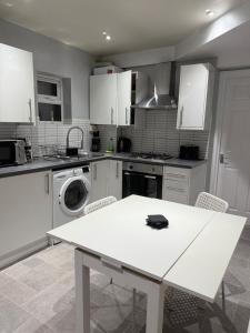 a kitchen with a white table and a washing machine at Stylish 2-Bed Garden Flat, 5 Mins to Brixton in London