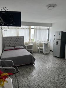 a bedroom with a bed and a table and a refrigerator at Laguito Suites Cartagena in Cartagena de Indias