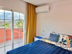a bedroom with a blue bed and a balcony at Sunset Apartment 5 & Heated Pool in Los Cristianos +24 photos