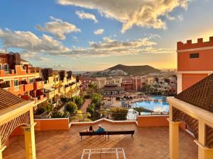 a couple sitting on a bench on the balcony of a resort at Sunset Apartment 5 & Heated Pool in Los Cristianos