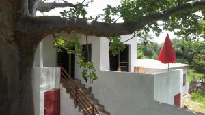 KafountineKASA BOUBAK avec cuisine extérieure à 50 M DE LA PLAGE的白色的房子,有树和红伞