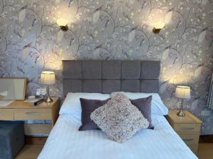 a bedroom with a bed with two night stands and two lamps at Whortleberry Studio B & B in Porlock