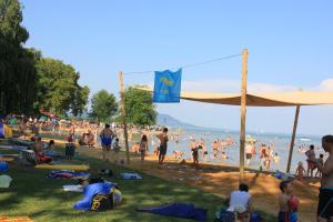 a crowd of people on a beach with a flag at Németh Apartmanház in Balatongyörök