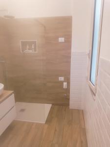 a bathroom with a shower with a wooden floor at Il Nido dAmare in Ladispoli +4 photos