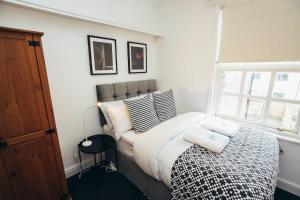 ein Schlafzimmer mit einem Bett mit Kissen und einem Fenster in der Unterkunft 4BR Town House, Self Check In, Parking, By DerBnB in Derby