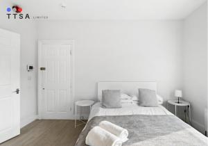 ein weißes Schlafzimmer mit einem Bett mit zwei Handtüchern darauf in der Unterkunft 1-Bedroom Apartment near East Croydon Station - 2 in South Norwood