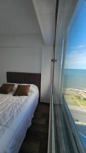 a bedroom with a bed and a large window at Departamento frente al mar con cochera in Mar del Plata +31 photos