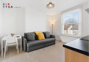 ein Wohnzimmer mit Sofa und Tisch in der Unterkunft 1-Bedroom Apartment near East Croydon Station - 2 in South Norwood