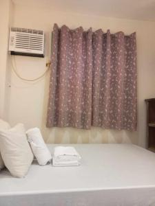 a bed with two white pillows and a window at Toto s House Junior Suite in Puerto Princesa City