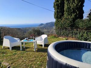 eine Terrasse mit 2 Stühlen, einem Tisch und einem Pool in der Unterkunft Elegante villa panoramica con giardino e idromassaggio a 10 minuti dal mare in Castellabate + 64 Fotos