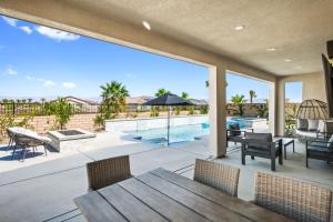 Un patio con mesa y sillas y una piscina. en Luxury Desert Escape Private Pool Putting Green Outdoor Oasis, en La Quinta