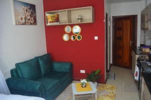 ein Wohnzimmer mit einem grünen Sofa und einer roten Wand in der Unterkunft Simba Bnb Karen in Nairobi