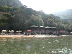 a beach with umbrellas and chairs and a body of water at Hotel Club Torre Capovento in Sperlonga