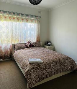 a bedroom with a large bed with a window at Werribee 3 BR Holiday Home in Werribee