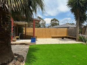 a backyard with a wooden fence and a green lawn at Werribee 3 BR Holiday Home in Werribee