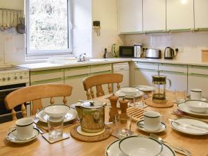 een keuken met een houten tafel met borden en glazen bij Thurston View in Coniston +8 foto's