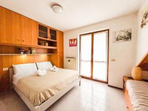 a bedroom with a bed and a large window at Villetta a schiera con giardino privato in Castione della Presolana