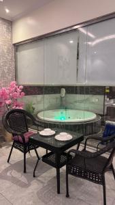 - un bain à remous dans une pièce avec deux chaises et une table dans l'établissement شاليهات بالي, à Jilhayah