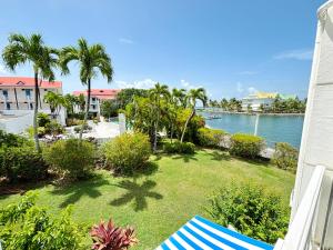 a lawn with palm trees and a body of water at Bleu Lagon - Vue mer, Piscine, Marina et Golf in Saint-François
