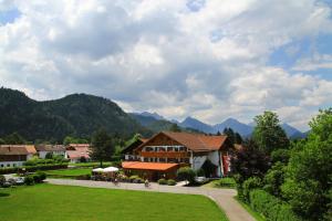 a building with a green lawn and mountains in the background at Helmerhof in Schwangau