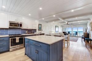 a large kitchen with blue cabinets and a large island at High End Coastal Feel Condo in Fernandina Beach +47 photos