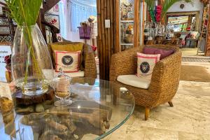 a glass table with two wicker chairs and a table with a vase at Casa Jaguar Hotel & Boutique in Acapulco