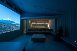 a woman sitting in a room with a view of a mountain at 富士山望むプライベートヴィラ 900平方メートルの敷地を貸切利用 憩 ikoi Fuji サウナ 4Kシアター in Fujikawaguchiko