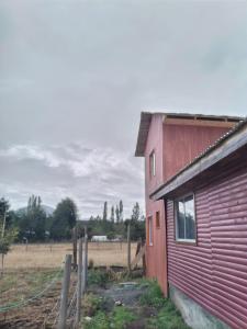 un fienile rosso con una recinzione accanto a un campo di cabañas huilipan a Pucura