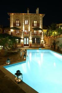 a large swimming pool in front of a house at night at Maritsas Hotel & Suites in Portaria