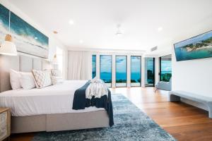 ein weißes Schlafzimmer mit einem großen Bett und Glasfenstern in der Unterkunft CoralAir Whitsundays in Airlie Beach + 24 Fotos