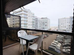 a table and chairs on a balcony with a view of a city at Apartment near Belgian Coast Beach in Oostduinkerke