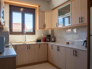 a kitchen with wooden cabinets and a sink and a window at Villa in Sfakaki with Pool near Beach in Sfakaki