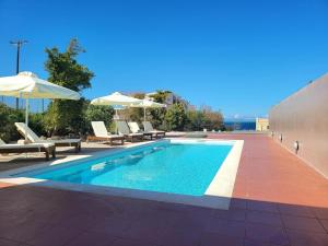 a swimming pool with chairs and umbrellas on a building at Villa in Hersonissos by Sandy Beach & Pool in Hersonissos